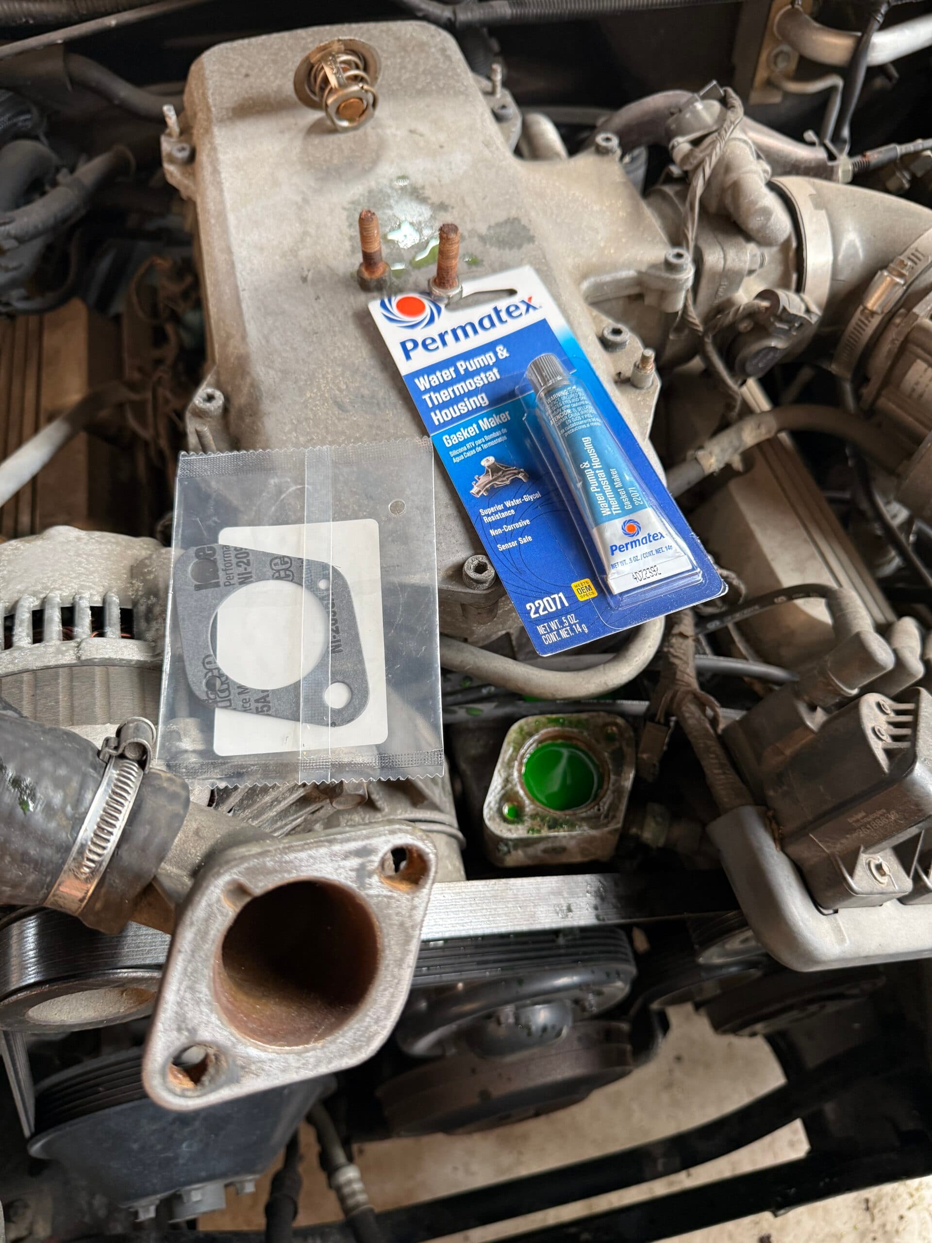 Replacement thermostat housing gasket beside the removed Commodore housing